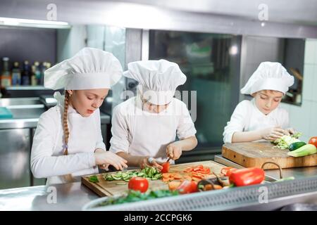 Kinder mahlen Gemüse in der Küche eines Restaurants. Stockfoto