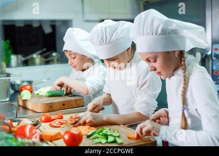 Kinder mahlen Gemüse in der Küche eines Restaurants. Stockfoto