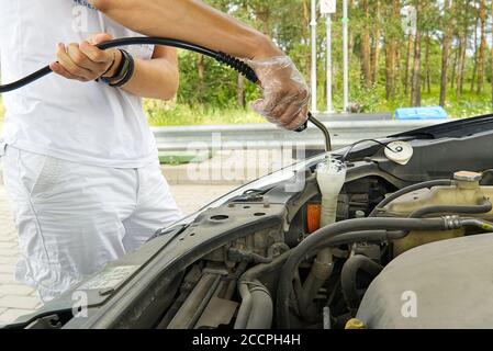 Scheibenwaschflüssigkeit an der Gasolinstation durch den Fahrer nachfüllen. Nahaufnahme der Zugabe von Windschutzscheibe Waschflüssigkeit auf einem Auto. Car Service-Konzept. Stockfoto