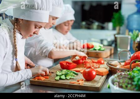 Kinder mahlen Gemüse in der Küche eines Restaurants. Stockfoto