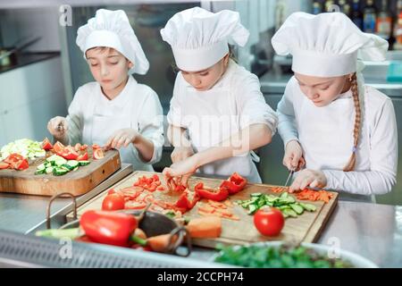 Kinder mahlen Gemüse in der Küche eines Restaurants. Stockfoto