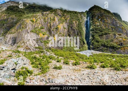 Die Berge ragen über dem Tal des Franz-Josef-Gletschers an der Westküste Neuseelands. Gemäßigte Regenwälder wachsen überall, wo sie können und die dunklen c Stockfoto