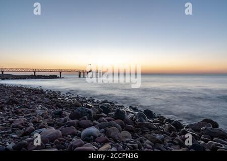 Sonnenaufgang von einem Kiesstrand mit einem Gehweg zum Meer Stockfoto