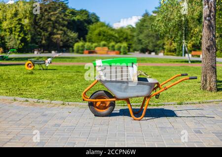 Schubkarre auf einem grünen Grasfeld. Garten Metall Schubkarre Wagen. Stockfoto