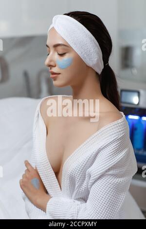 Gesichtspeeling-Maske, Wellness-Schönheitsbehandlung, Hautpflege. Frau bekommt Gesichtsbehandlung von Kosmetikerin im Spa-Salon Stockfoto