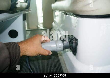 Hand hält elektrischen Stecker zu starten Laden Elektroauto. Transporttechnik Konzept Stockfoto