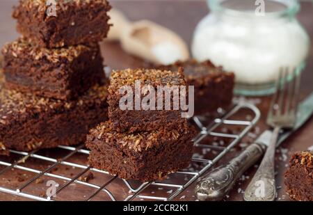 Frisch gebackene hausgemachte vegane Brownie mit gemahlener Kokosnuss und Schokolade Scheiben in quadratischen Portionen geschnitten. Köstliches amerikanisches Dessert. Selektiver Fokus Stockfoto