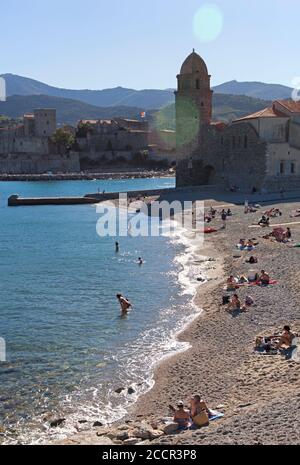 Sonnenanbeter am sicheren Hafenstrand von Collioure unter dem Historischer Leuchtturm Stockfoto