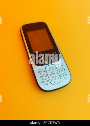 Altes Mobiltelefon. Handy isoliert auf orangefarbenem Hintergrund, vintage Handy, vintage Stil Stockfoto