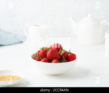 Erdbeeren in einer weißen Schüssel, auf einem weißen Tisch, Frühstück am Morgen, Sommeressen Stockfoto