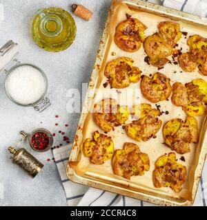 Im Ofen gebackene ganze zerkleinerte und knusprige Kartoffel mit grobem Meersalz, Olivenöl, Knoblauch, Pfeffer und Thymian in metallischen Tablett. Geröstete Kartoffelpüree. Austr Stockfoto