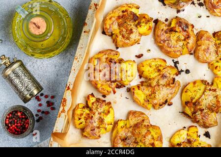 Im Ofen gebackene ganze zerkleinerte und knusprige Kartoffel mit grobem Meersalz, Olivenöl, Knoblauch, Pfeffer und Thymian in metallischen Tablett. Geröstete Kartoffelpüree. Austr Stockfoto