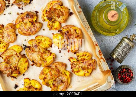 Im Ofen gebackene ganze zerkleinerte und knusprige Kartoffel mit grobem Meersalz, Olivenöl, Knoblauch, Pfeffer und Thymian in metallischen Tablett. Geröstete Kartoffelpüree. Austr Stockfoto