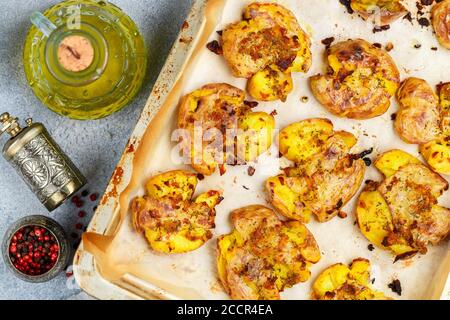 Im Ofen gebackene ganze zerkleinerte und knusprige Kartoffel mit grobem Meersalz, Olivenöl, Knoblauch, Pfeffer und Thymian in metallischen Tablett. Geröstete Kartoffelpüree. Austr Stockfoto