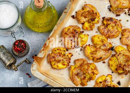 Im Ofen gebackene ganze zerkleinerte und knusprige Kartoffel mit grobem Meersalz, Olivenöl, Knoblauch, Pfeffer und Thymian in metallischen Tablett. Geröstete Kartoffelpüree. Austr Stockfoto