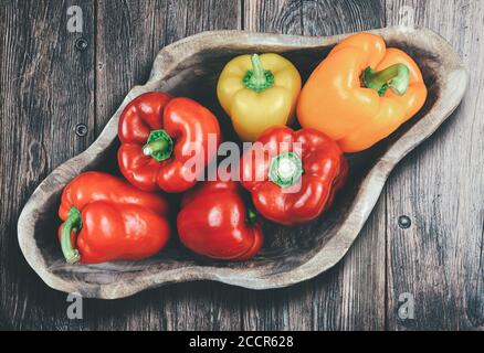 Direkt über dem Blick auf frische bunte Paprika in Holz Schüssel auf dem Tisch Stockfoto