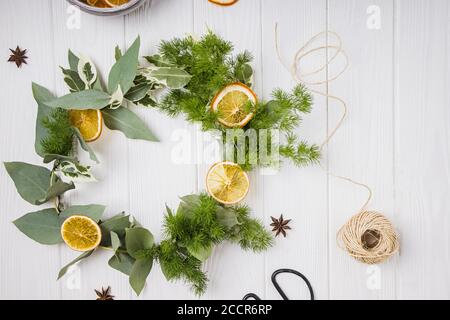 Handgemachter weihnachtskranz mit trockenen Orangen auf weißem Tisch, Draufsicht Stockfoto