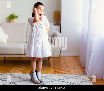 Kleines Mädchen, das Spaß hat, die High Heels der Mutter zu Hause zu tragen Stockfoto