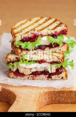 Köstliches Pute- oder Hühnerbrot mit Brie- oder Camembert-Käse, Salat und Preiselbeere (Preiselbeere, Preiselbeere) Chutney auf Getreidebrot mit Flachs siehe Stockfoto