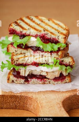 Köstliches Pute- oder Hühnerbrot mit Brie- oder Camembert-Käse, Salat und Preiselbeere (Preiselbeere, Preiselbeere) Chutney auf Getreidebrot mit Flachs siehe Stockfoto