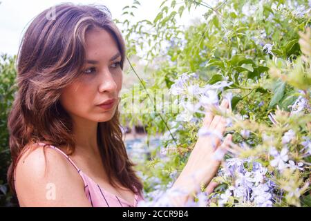 Junge Frau beobachtet Wildblumen. Mittlere Nahaufnahme. Horizontale Ansicht. Stockfoto