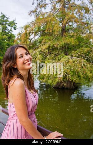 Junge Frau, die um einen See herum erkundet und die Kamera lächelt. Stockfoto