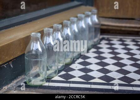 Leere Milchflaschen vor der Haustür, die auf die Abholung warten Stockfoto