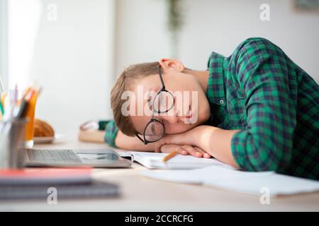 Erschöpft Schuljunge in Brille schlafen am Schreibtisch Stockfoto