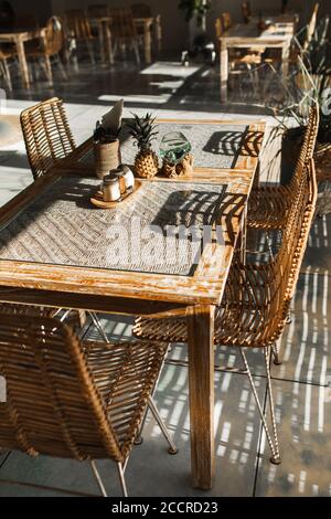 Handgefertigte Rattan-Stühle und Holztisch. Modernes Möbeldesign. Sommercafe Terrasse. Stockfoto