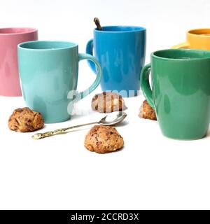 Viele bunte Tassen Zitronentee und hausgemachte Kekse auf einem weißen Tisch. Stockfoto