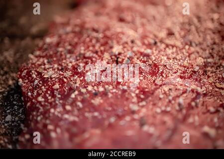 Pfeffer und Gewürze auf dem rohen Fleischsteak aus nächster Nähe mischen Stockfoto