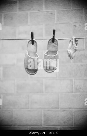 Weibliche Pantoffeln und Socken werden im Sommer an einer Wäscheleine getrocknet. BW-Foto. Stockfoto