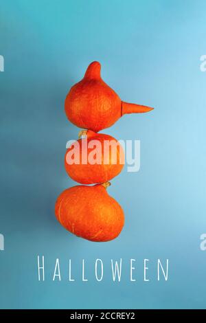 Ein Schneemann mit einer Karottennase aus drei orangefarbenen Kürbissen auf blauem Hintergrund. Halloween-Konzept. Stockfoto