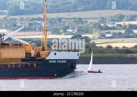 Hopper Dredger, Sand Fulmar, mit Bugwelle vorbei an einem kleinen Vintage-Segelboot aus Holz. Klein und groß, Umfang der verschiedenen Fluss Verkehr auf der Themse Stockfoto