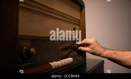 Mann Hand auf der Suche nach dem Radiosender auf dem Vintage-Radio. Hochwertige Fotos Stockfoto