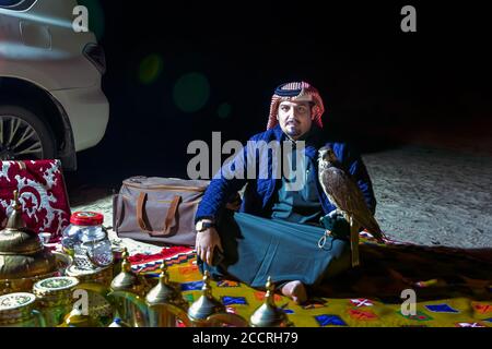 Saudi-arabischer Mann hält Falken in der Hand in der Wüste Nacht. Al-Sarar, Saudi-Arabien. Stockfoto