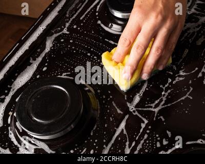 Reinigung der Küche, Reinigung der Oberfläche auf dem Gasherd mit einem Waschlappen, Haushaltsküchengeräte. Stockfoto