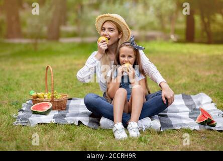 Glückliche Mutter Und Tochter Essen Äpfel Sitzen Auf Plaid Outdoor Stockfoto