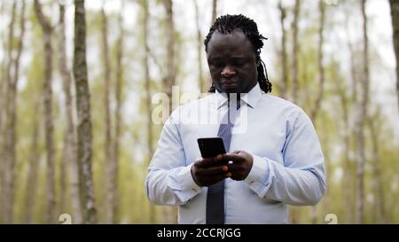Afrikanischer Mann mit Smartphone in der Natur. Hochwertige Fotos Stockfoto