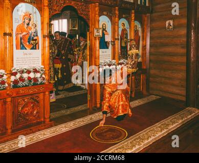 Adygea, Russland - 8. November 2017: Der junge Mann Subdiakon richtet den Teppich vor dem Altar in einer orthodoxen Kirche bei der Gottesliturgie Stockfoto