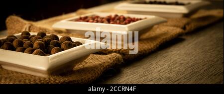 Schüssel voll mit Gewürzen auf Sackleinen und einem dunklen Holzhintergrund. Natürliche Gewürze, Vintage alte Gewürzthema. Stockfoto