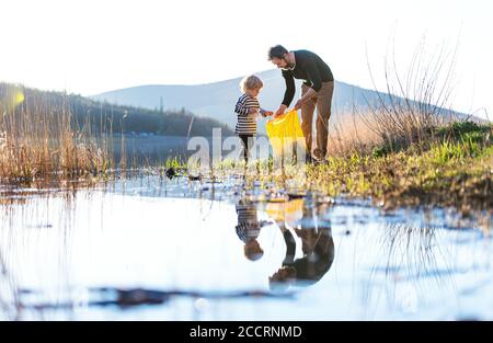 Vater mit kleinen Sohn sammeln Müll im Freien in der Natur, plogging Konzept. Stockfoto