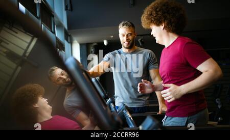 Übergewichtiger junger Mann trainiert mit persönlichem Trainer die Sporthalle Stockfoto