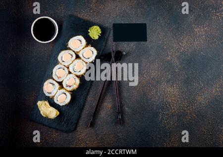 Maki-Brötchen auf Steinplatte mit Soßen, Ingwer und Wasabi Stockfoto