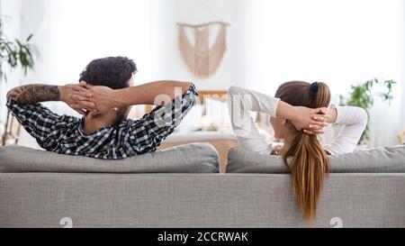 Ruhe nach der Reinigung in der neuen Wohnung. Mann und Frau sitzen auf der Couch und schauen sich im Inneren an Stockfoto