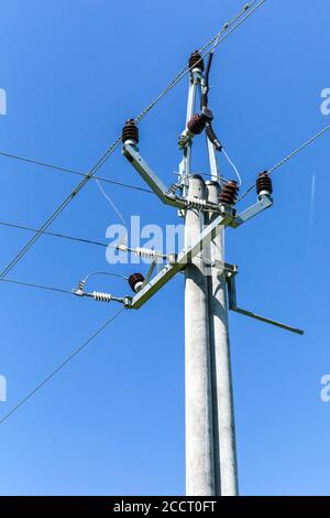 Energiekonzept. Hochspannungsmast-Stromleitungen gegen den blauen klaren Himmel. Dreiphasige Stromleitung zum Drehen. Stromverteilung. Stockfoto