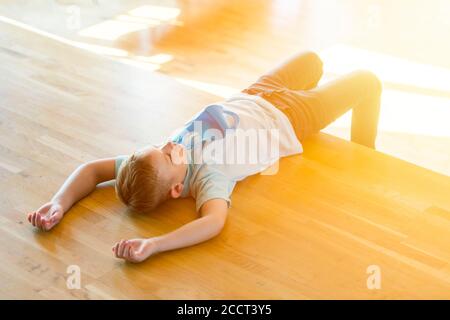 Gestresstes müde erschöpftes Kind mit blauer Maske in einer Lektion. Sicher zurück in die Schule während Pandemiekonzept. Soziale Distanzierung gegen COVID-19 Stockfoto