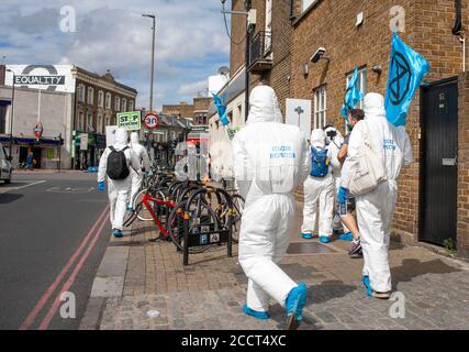 Extinction Rebellion Mitglieder, in sauberen Anzügen gekleidet, marschieren in Richtung Barclays in Balham, um zu protestieren, dass die Banken neue Investitionen in fossile Brennstoffe fortsetzten. Stockfoto