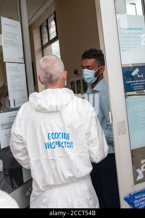 London, Großbritannien. August 2020. Extinction Rebellion Mitglied, in einem sauberen Anzug gekleidet, interagiert mit Barclays Mitarbeiter in Balham, South London. XR Stockfoto