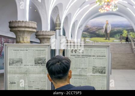 Ein Pendler liest eine Zeitung auf einem Bahnsteig einer U-Bahnstation des Pjöngjang, Nordkorea Stockfoto